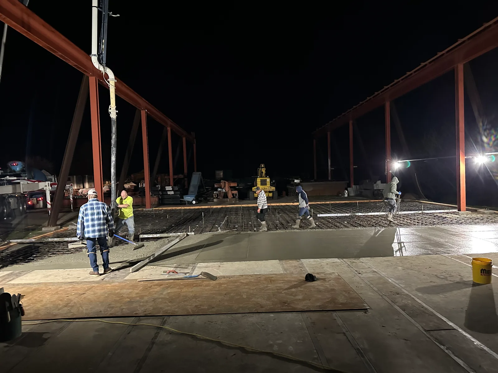 Crew finishing a concrete slab under lights at night